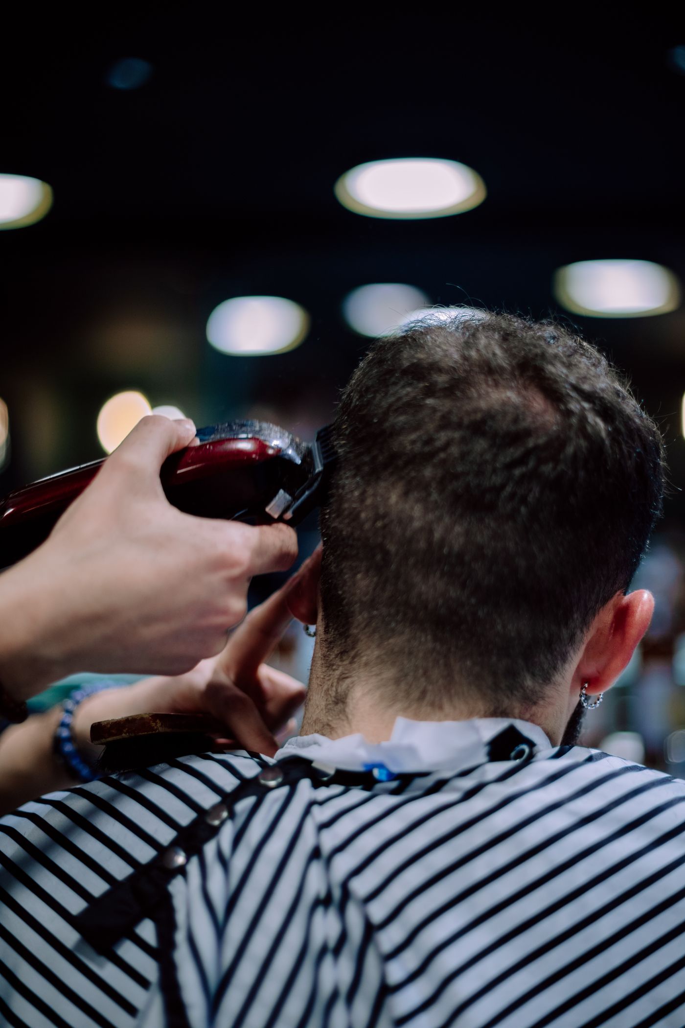 Barbeiro cortando o cabelo de um cliente com máquina